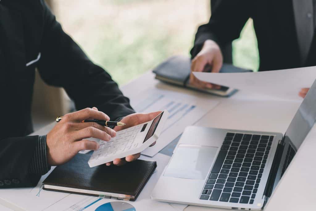 accountant using a white calculator with macbook in background