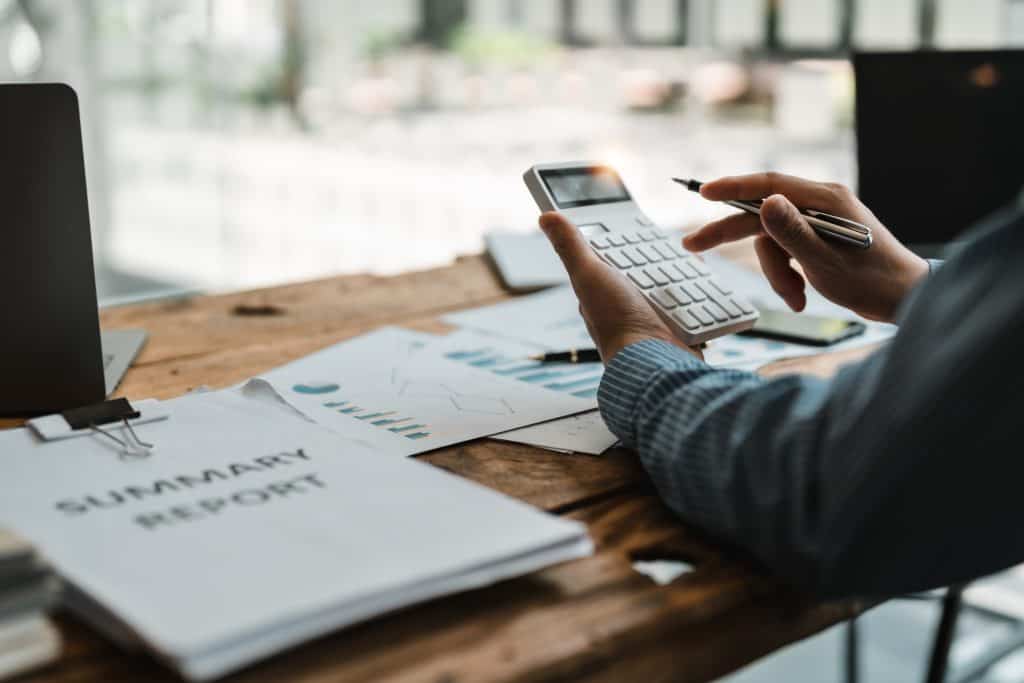 Person using calculator for financial summary report.