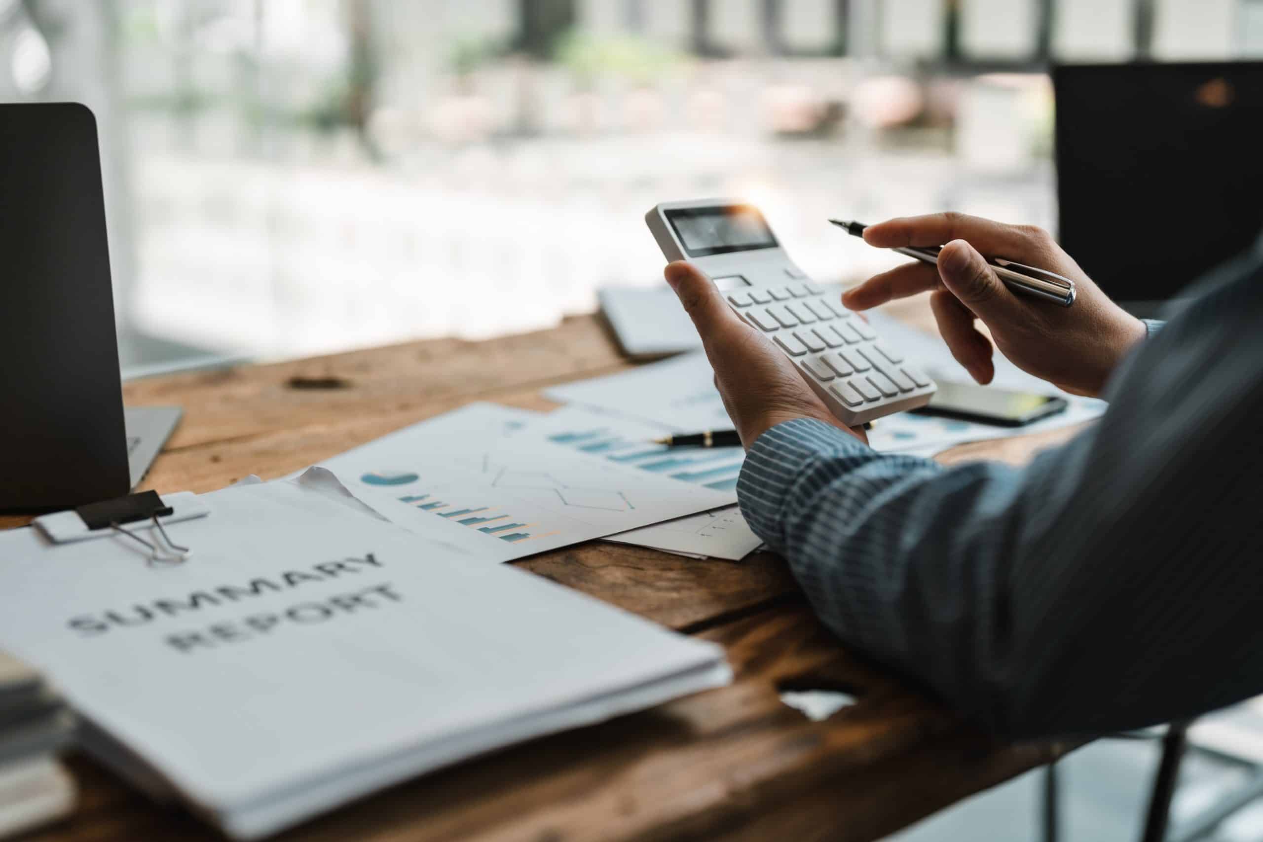 Person using calculator for financial summary report.
